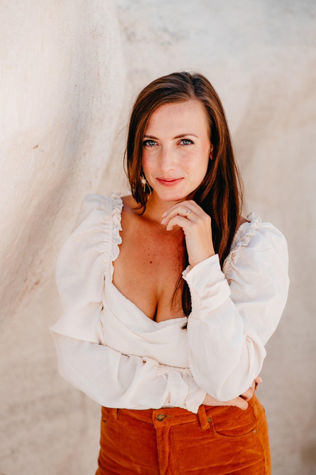Ruby, smiling softly, in a cream blouse against a white canyon wall